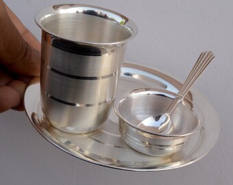 May include: A silver serving set with a small bowl, a spoon, and a cup on a silver tray. The set has a traditional design with engraved lines.
