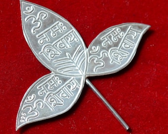 May include: A silver leaf charm with three leaves, each with the inscription "Om Namah Shivaya" in Sanskrit. The charm is marked "925" for sterling silver.