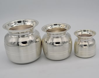 May include: Three silver pots of varying sizes, with a shiny, polished finish. The pots have a rounded body and a slightly flared rim.
