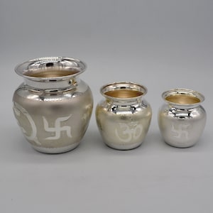 May include: Three silver pots with religious symbols engraved on them. The largest pot has a swastika symbol, the middle pot has an Om symbol, and the smallest pot has a swastika symbol.