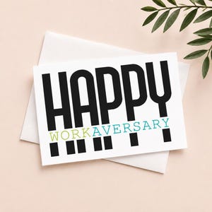 Może przedstawiać: Biała kartka z życzeniami z napisem "HAPPY WORKAVERSARY" w kolorze czarnym, zielonym i turkusowym. Karta znajduje się na białej kopercie, z jasnoróżowym tłem i zielonymi liśćmi w rogu.