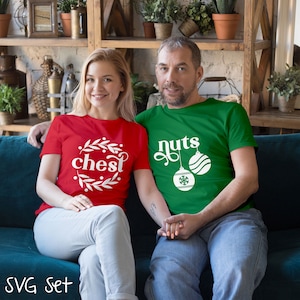 May include: A couple wearing matching Christmas themed shirts. The woman's shirt is red and says "chest" with a wreath around the word. The man's shirt is green and says "nuts" with two ornaments hanging from the word.