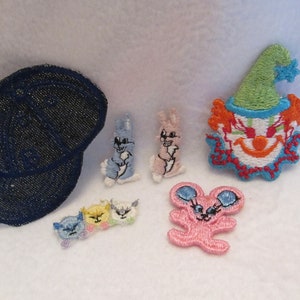 May include: A set of seven embroidered iron-on patches featuring a blue denim baseball cap, two pink bunnies, a blue bunny, three kittens, and a pink mouse with a clown face.