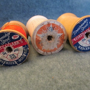 May include: Three wooden spools of Coats & Clark's thread. The spools are labeled "Dressmaker Spool" and have a price of 39 cents. The thread is mercerized and comes in sizes 50 and 600.
