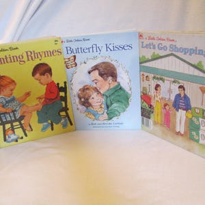 May include: Three vintage children's books are displayed, featuring colorful illustrations and titles. The titles include "Counting Rhymes," "Butterfly Kisses," and "Let's Go Shopping!" The books are in good condition, with bright covers.