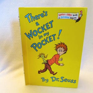 May include: A yellow children's book titled "There's a Wocket in my Pocket!" by Dr. Seuss. The cover features a cartoon illustration of a boy and a creature. The book is part of the "Bright & Early Books for Beginning Beginners" series.