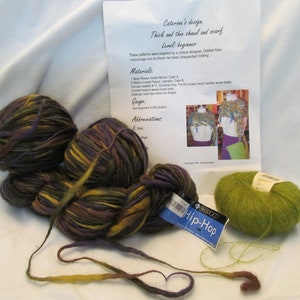 May include: Two balls of yarn in shades of purple, green, and brown, and one ball of green yarn. The yarn is labeled "Hip-Hop". The image also includes a sheet of paper with instructions for a knitting project.