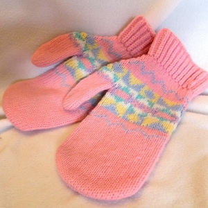Puede incluir: Un par de mitones rosas tejidos. Los mitones tienen un puño acanalado y un patrón geométrico en colores pastel en la parte superior. Hechos de hilo suave y cálido, son perfectos para el invierno.