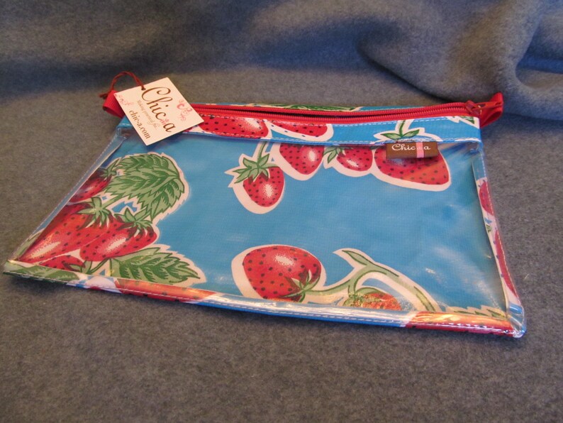 Puede incluir: Una bolsa de pl&aacute;stico transparente con cremallera, con fondo azul y cremallera roja. La bolsa tiene un estampado de fresas y el texto "Chica" en la parte delantera.