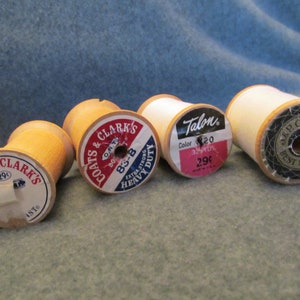 May include: Four spools of thread, two with Coats & Clark's labels, one with a Talon label, and one with a J&P Coats label. The spools are wooden and have different colors of thread.
