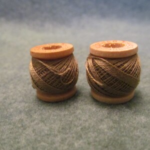 May include: Two spools of brown thread wound on wooden bobbins.