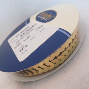 May include: A spool of gold sequin trim. The trim is wound around a white cardboard spool with a blue and cream-colored label. The label has the Wrights logo and product information.