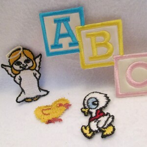 May include: A set of four embroidered iron-on patches. The patches feature a yellow chick, a white angel with a halo, a white duck with a red bib, and three alphabet blocks with the letters A, B, and C. The blocks are blue, yellow, and pink.