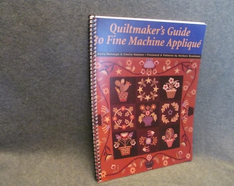 May include: A spiral bound book titled "Quiltmaker's Guide to Fine Machine Appliqué" by Karla Menaugh & Cherie Ralston. The cover features a colorful quilt design with various floral and geometric patterns.
