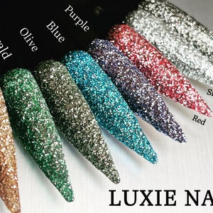 Puede incluir: Una colección de uñas postizas con purpurina en varios colores, incluyendo dorado, esmeralda, oliva, azul, morado, rojo, plateado y negro. Las uñas están dispuestas en fila, mostrando las diferentes tonalidades. El texto "LUXIE NAIL" se encuentra en la parte inferior.