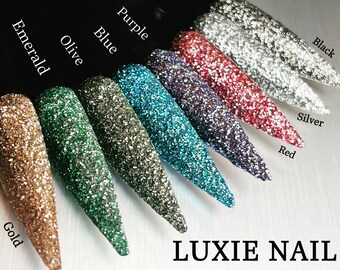 May include: A collection of glitter nail tips in various colors, including gold, emerald, olive, blue, purple, red, silver, and black. The tips are arranged in a row, showcasing the different shades. The text "LUXIE NAIL" is at the bottom.