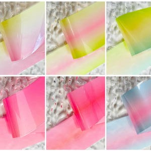 Puede incluir: Una colección de diez imágenes que muestran tiras de arte de uñas translúcidas y coloridas. Cada tira muestra un degradado de colores, incluyendo rosa, amarillo, verde y azul, con un acabado brillante. Las tiras están dispuestas sobre una superficie texturizada.
