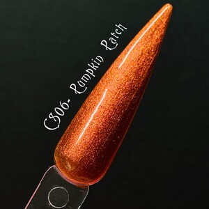 Puede incluir: Primer plano de una pequeña botella de esmalte de uñas naranja con purpurina. La botella está etiquetada como "C306 - Pumpkin Patch".