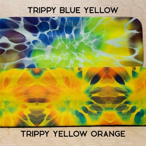 Op de afbeelding: Twee rechthoekige brillenkokers met kleurrijke tie-dye patronen. De bovenste koker heeft een blauw, geel en groen ontwerp, met de tekst "Trippy Blue Yellow". De onderste koker heeft een geel en oranje ontwerp, met de tekst "Trippy Yellow Orange".