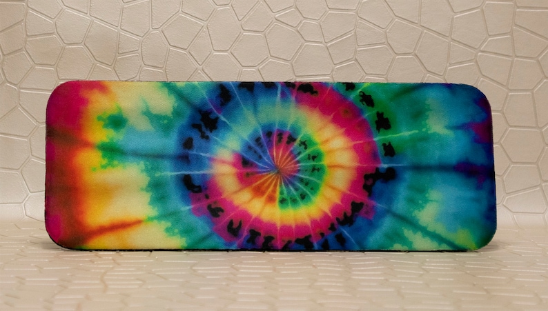 Op de afbeelding: Rechthoekige brillenkoker met een levendig tie-dye patroon. Het ontwerp toont een spiraal van kleuren, waaronder roze, geel, groen en blauw. De koker heeft afgeronde hoeken en een zwarte rand.