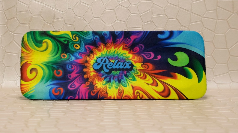 Op de afbeelding: Een rechthoekige etui met een levendig, psychedelisch ontwerp. De etui heeft een wervelend patroon van kleuren, waaronder geel, groen, blauw, roze en paars. Het woord "Relax" staat in een blauw, retro lettertype in het midden.