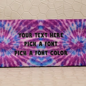 Op de afbeelding: Rechthoekige etui met een tie-dye ontwerp in paarse en blauwe tinten. De tekst "YOUR TEXT HERE, PICK A FONT, PICK A FONT COLOR" is in zwart gedrukt. De etui heeft afgeronde hoeken.