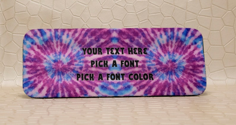 Op de afbeelding: Rechthoekige etui met een tie-dye ontwerp in paarse en blauwe tinten. De tekst "YOUR TEXT HERE, PICK A FONT, PICK A FONT COLOR" is in zwart gedrukt. De etui heeft afgeronde hoeken.