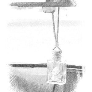 May include: A clear, rectangular car air freshener with a floral design inside, hanging from a string. The air freshener is suspended from a car's rearview mirror.