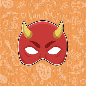 May include: A red devil mask with yellow horns and white eyes. The mask is on a background with a pattern of hearts, swirls, and the words "Vanilla", "Sugar", "Butter", and "Milk".