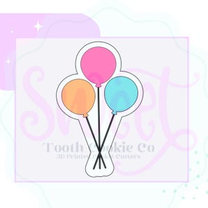 May include: A cookie cutter in the shape of three balloons tied together. The balloons are pink, orange, and blue.