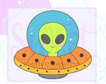 May include: A cartoon illustration of an alien in a UFO cookie cutter. The alien has a green head and a blue helmet. The UFO is orange with black dots and the text "Tooth Cookie Co" is visible.