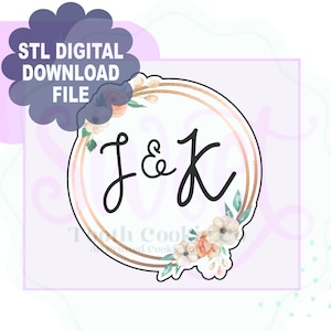 Puede incluir: Un archivo de descarga digital para un cortador de galletas impreso en 3D en forma de círculo con un borde de doble anillo. El círculo tiene un diseño floral con las letras J & K en el centro.