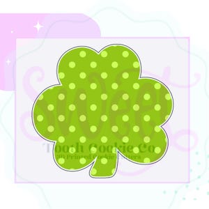 May include: A green shamrock-shaped cookie cutter with a polka dot pattern. The word "WEA" is visible on the shamrock. The text "Toooh Cookie Co. 3D Printed Cookie Cutters" is also visible.