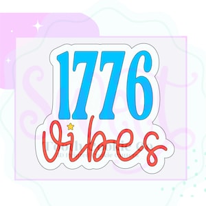 May include: A white cookie cutter with the text "1776 Vibes" in blue and red. The number "1776" is in a bold, sans-serif font, and the word "Vibes" is in a cursive font with a small star above the "i".