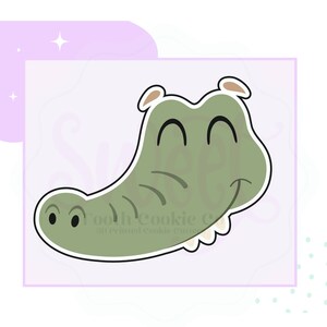 May include: A green cartoon alligator with a big smile and closed eyes. The alligator has a white outline and is on a light purple background.
