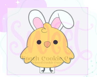 May include: A yellow chick-shaped cookie cutter with bunny ears. The chick has black eyes and an orange beak. The bunny ears are white with pink inner ears. The text "Tooth Cookie Co. Printed Cookie Cutters" is visible.