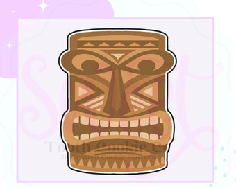 Puede incluir: Un cortador de galletas con forma de máscara tiki marrón con un diseño detallado. La máscara tiene forma rectangular con boca ancha, ojos grandes y patrones geométricos. El texto "Tooth Cookie Co." está en la parte inferior.