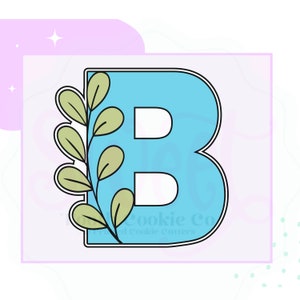 May include: A blue cookie cutter in the shape of the letter B with a green leafy vine design. The cookie cutter is outlined in black.