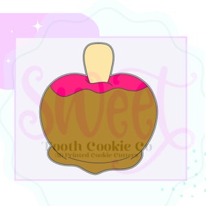 May include: A brown and pink cookie cutter shaped like a candy apple with a stick. The cookie cutter is labeled "Tooth Cookie Co. 3D Printed Cookie Cutters".