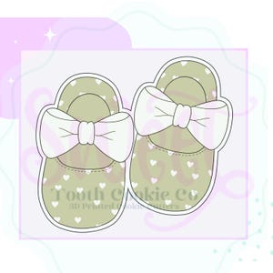 May include: Two green baby shoes with white polka dots and white bows. The shoes are outlined in white.