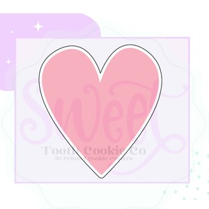 May include: A pink heart-shaped cookie cutter with a white outline. The cutter is on a light purple background with white polka dots.