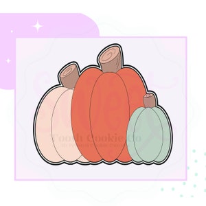 May include: A cookie cutter featuring three pumpkins in varying sizes and colors. The pumpkins are outlined in black, with a light peach, orange, and light green color scheme. The stems are brown and have a spiral design.