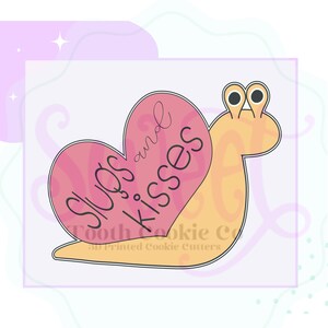 May include: A pink and yellow cookie cutter shaped like a snail with a heart on its back. The heart has the text "Hugs and Kisses" written on it.
