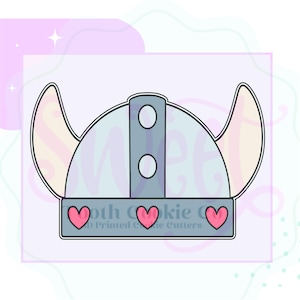 May include: A light blue Viking helmet cookie cutter with two curved horns and three pink hearts. The helmet has two circular rivets and a rectangular band. The text "Moth Cookie Co" is printed on the bottom.