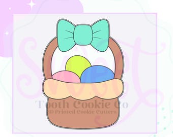 May include: A cookie cutter in the shape of an Easter basket with a bow on top. The basket is brown and contains three colorful eggs: yellow, pink, and blue. The text "Tooth Cookie Co" is printed on the bottom.