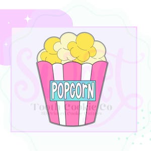 May include: A pink and white striped popcorn bucket cookie cutter with the word "POPCORN" in blue letters on the front.