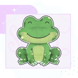 May include: A green cartoon frog with a big smile and white spots. The frog is sitting with its legs crossed.