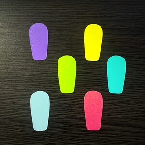 Peut inclure: Six découpes de papier rectangulaires de couleurs différentes, dont le violet, le jaune, le vert, le bleu et le rose, sont disposées sur une surface en bois foncé.