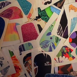 May include: A collection of colorful and patterned stickers, including a sticker with the text "Ride like the wind, Bullseye!" and a sticker with a cartoon image of Woody from Toy Story.