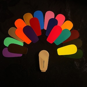 May include: A fan-shaped arrangement of 18 colorful, rounded, plastic pieces, with a beige hearing aid device in the center. The hearing aid device has the text "GoComGo" printed on it.